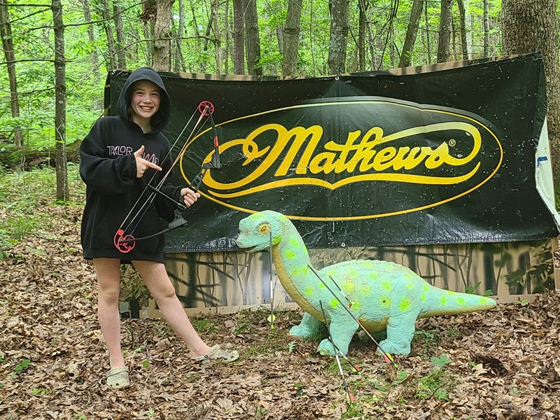 A camper with a bow at the archery range