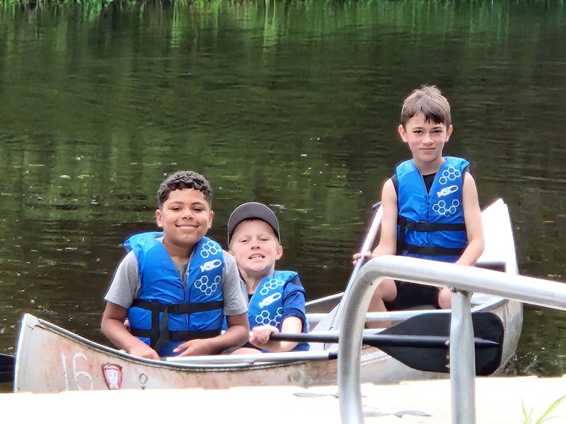 Campers in life jackets sitting in a canoe