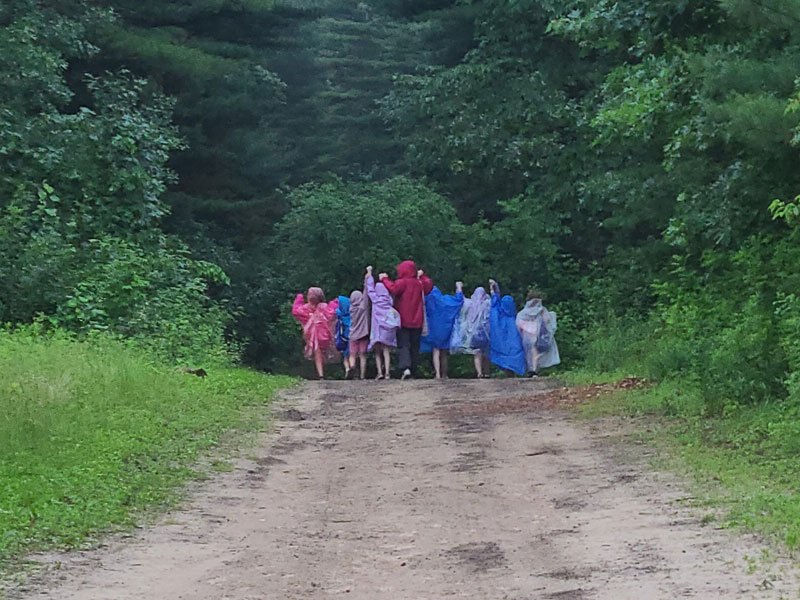 Campers in rain ponchos hiking down a trail